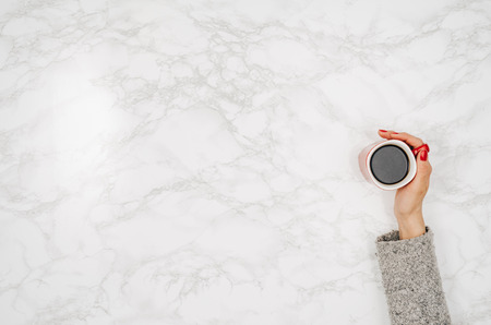 Woman hands holding coffee mug or cup on colorful table. Photograph taken from above, top view with copy spaceの写真素材
