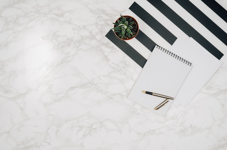 Blank notebook page on white marble table background. Image taken from above, top view. Frame composition with copy spaceの写真素材