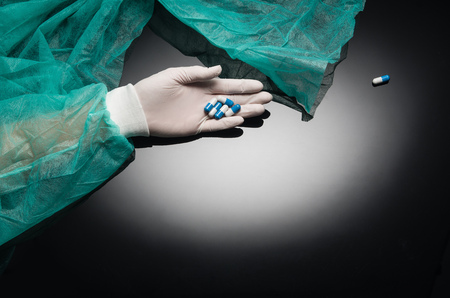 Doctors hand holding pills on black background with copy space. Medical concept frame with room for text or graphic elements.の写真素材