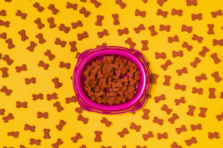 Dry dog food in bowl on yellow background top view.の写真素材