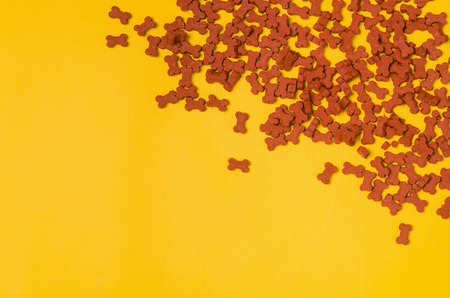 Dry dog food on yellow background top view. Pet feeding concept backgrounds with copy space. Frame composition.の写真素材