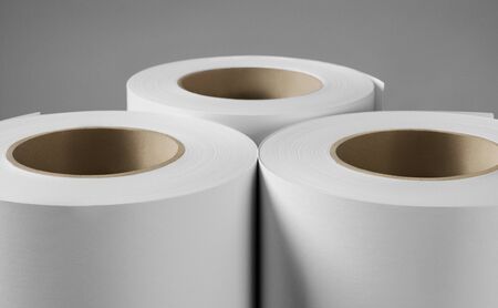 Blank white paper rolls isolated on gray background. Mockup paper for magazines, catalogs or newspapers isolated on gray backdrop, Printing house theme or wrapping paper for presentsの写真素材