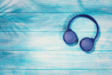 Blue wireless headphones on wooden background. Top view, copy spaceの写真素材