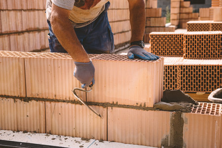 Professional construction worker laying bricks and mortar - building house wallの写真素材