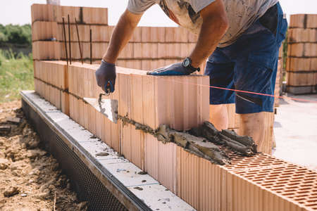 Professional construction worker laying bricks and mortar - building house wallの写真素材
