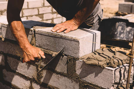 Professional construction worker laying bricks and mortar - building house wallの写真素材