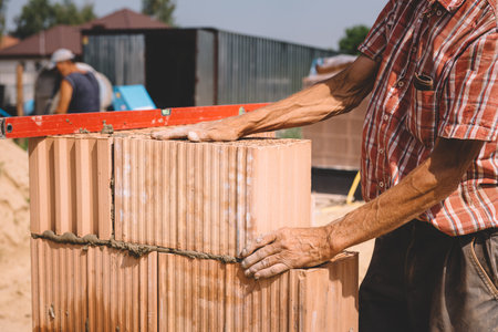 Professional construction worker laying bricks and mortar - building house wallの写真素材