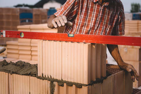 Professional construction worker laying bricks and mortar - building house wallの写真素材