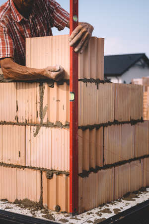 Professional construction worker laying bricks and mortar - building house wallの写真素材
