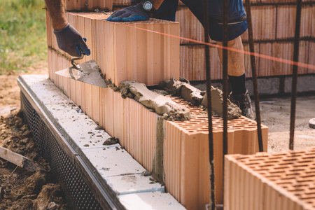 Professional construction worker laying bricks and mortar - building house wallの写真素材