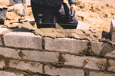Professional construction worker laying bricks and mortar - building house wallの写真素材