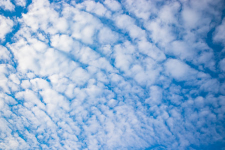 Tranquil blue sky with fluffy white clouds in a serene outdoor environment.の写真素材