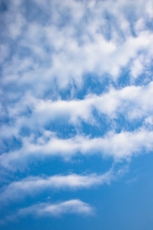Serenity in a clear blue sky with fluffy white clouds above a peaceful landscape.の写真素材
