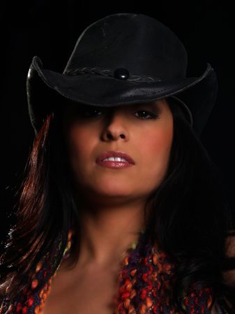 Beautiful latino girl with a hat posing over blackの写真素材