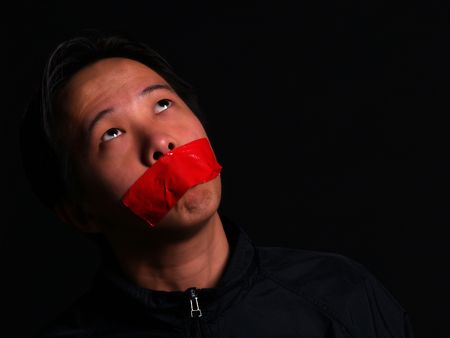 An Asian man held hostage with red tape over his mouth