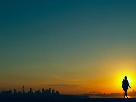Sunset over Sydney, Australia with a woman standing in front of the sun enjoying the viewの写真素材