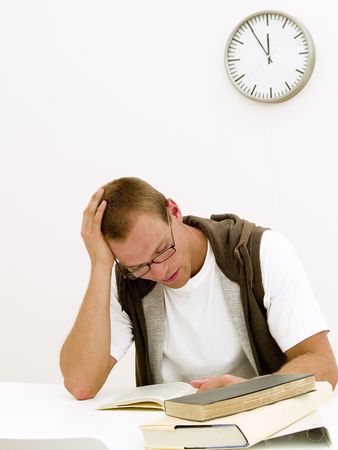 A young student working on his homework while the clock is tickingの写真素材