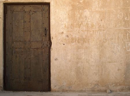 Old rusty door in a plastered wall with lots of copy spaceの写真素材