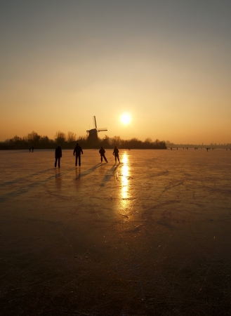 Ice skaters on a frozen lake in Rotterdam The Netherlands with a traditional windmill in the backの写真素材