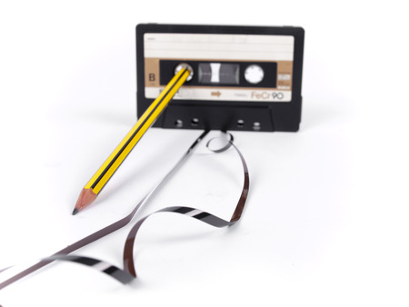 retro cassette with loose tape and a pencil to rewind over a white backgroundの写真素材