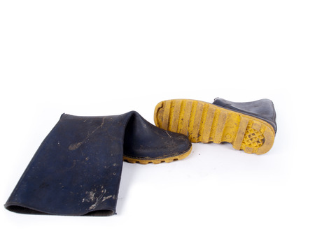 Pair of dark blue dirty rubber boots over a white backgroundの写真素材
