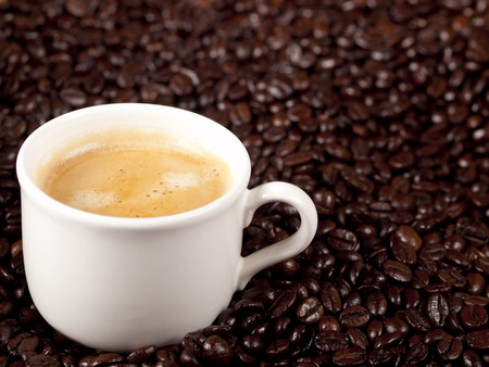 Fresh cup of dark roasted coffee with coffeebeans in the backgroundの写真素材