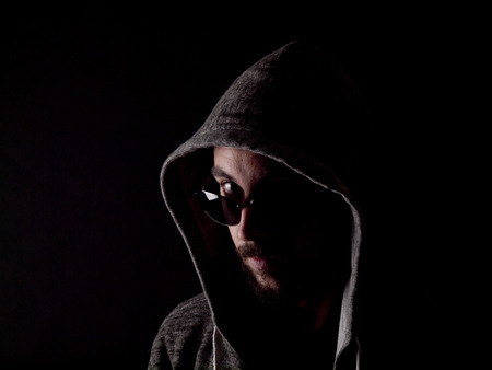 Low key image of a bearded man with a hoody and sunglassesの写真素材