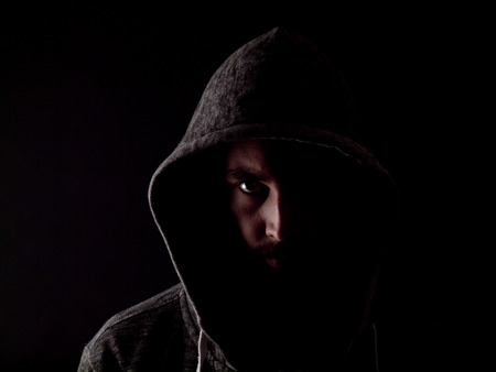 Low key image of a bearded man with a hoody