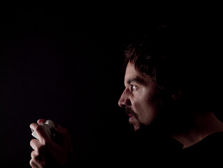 Low key image of a bearded man playing videogamesの写真素材