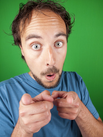 Man with surprised expression pointing at you over a green backgroundの写真素材