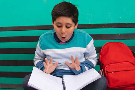 An elementary school boy with black hair dressed in a sweater is sitting in the park. The boy goes...