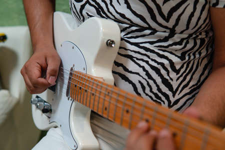 Doll holding his white electric guitar. Close up of a white guitar. You see the ropes with their...