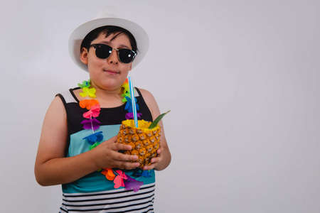 Boy dressed in beach clothes wearing a blue tank top, white hat and flower necklace. Boy dressed in...