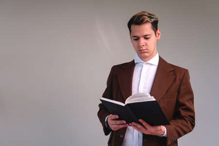 Concentrated businessman reading a book on a white background. Elegant man in a suit on an isolated...