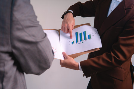 Two unrecognizable men in suits analyzing graphs. Businessmen working on a board to analyze the...