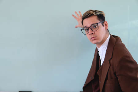 A teacher dressed in a brown coat, white shirt and glasses in front of the classroom. Attentive...