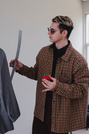 Fashion designer working in the studio. Tailor measuring a gray suit. Caucasian and blond clothing designer man. High quality photoの写真素材