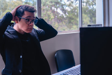 Office worker working at the desk in his office. A blonde Caucasian man dressed in a black shirt and glasses working on the computer at home. High quality photoの写真素材