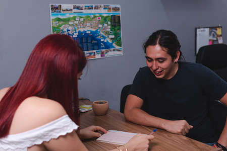 Red-haired travel agent at work about to close a sale with a client. Woman serving a client in her office. High quality photoの写真素材