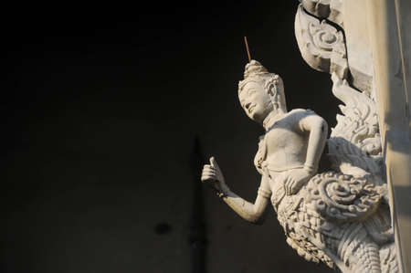 An Buddhist angel statue strick at the wall of construction site of Pagoda at Kaewfah temple in Nonthaburi province, Thailandの写真素材
