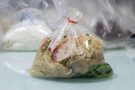 Egg noodle with red roasted pork (local Thai food) in plastic bagの写真素材