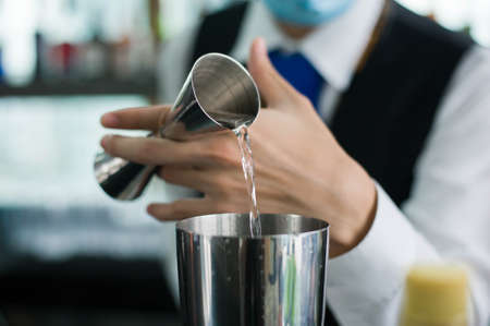 A bartender prepared a drink by dropping some ingredient into shaker