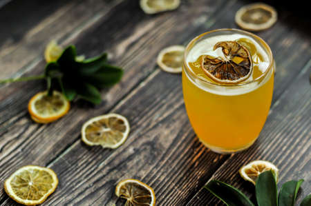 The signature yellow drink decorated with a dehydrated lemon wheel with wood backgroundの写真素材
