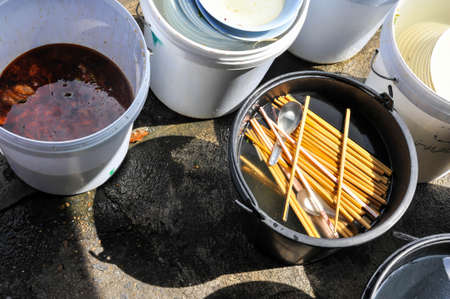 chopsticks in a plastic bowl at hand dish watching station of the noodle street food vendor in Bangkok Thailandの写真素材