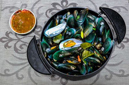 Top view of Thai style steamed mussels in a pot beside with Thai style spicy dipping sauceの写真素材