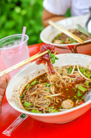 chopsticks with fermented raw beef the signature of thai noodle blood soup at Wat Maprao Tia Temple in Bangkok Thailandの写真素材
