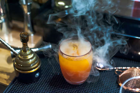 The Signature Orange color cocktail with smoke on the counter bar in Bangkok Thailandの写真素材