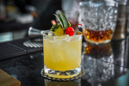 A Signature yellow drink decorated with fresh pineapple and red cherry stem in a restautant Bangkok Thailandの写真素材