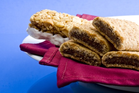 Wheat fig bars with nutty health bar on red cloth napkin and plate on blue backgroundの写真素材