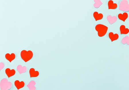 Pink and red paper hearts are opposite isolated on blue background.の写真素材